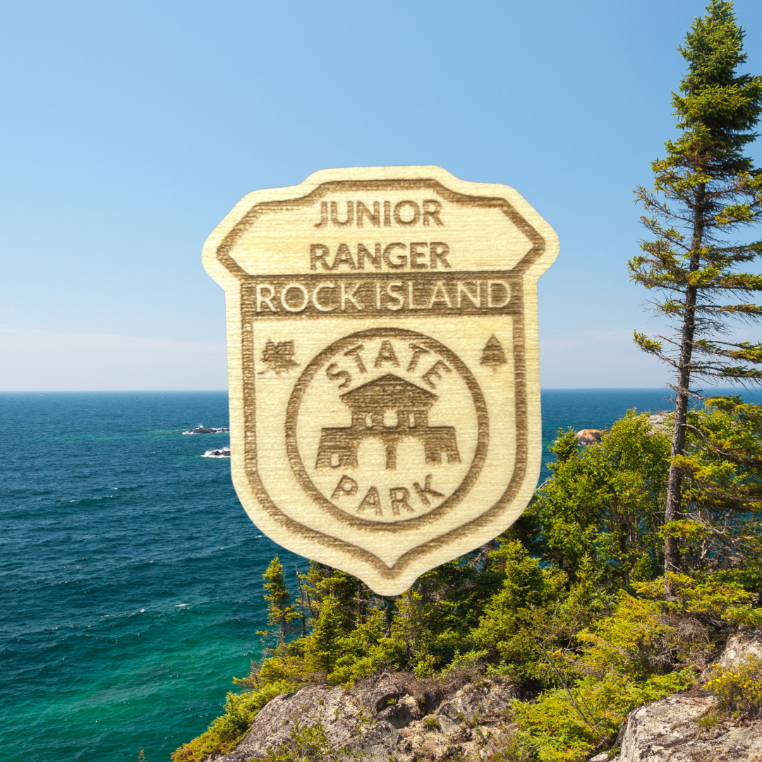 Wood Jr Ranger badge with the text: Junior Ranger, Rock Island State Park.  Photo background: large lake with a rocky shoreline and trees.