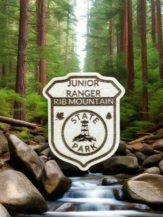 Wood badge shaped junior ranger pin with text Rib Mountain State Park and a observation tower on a hill icon. 