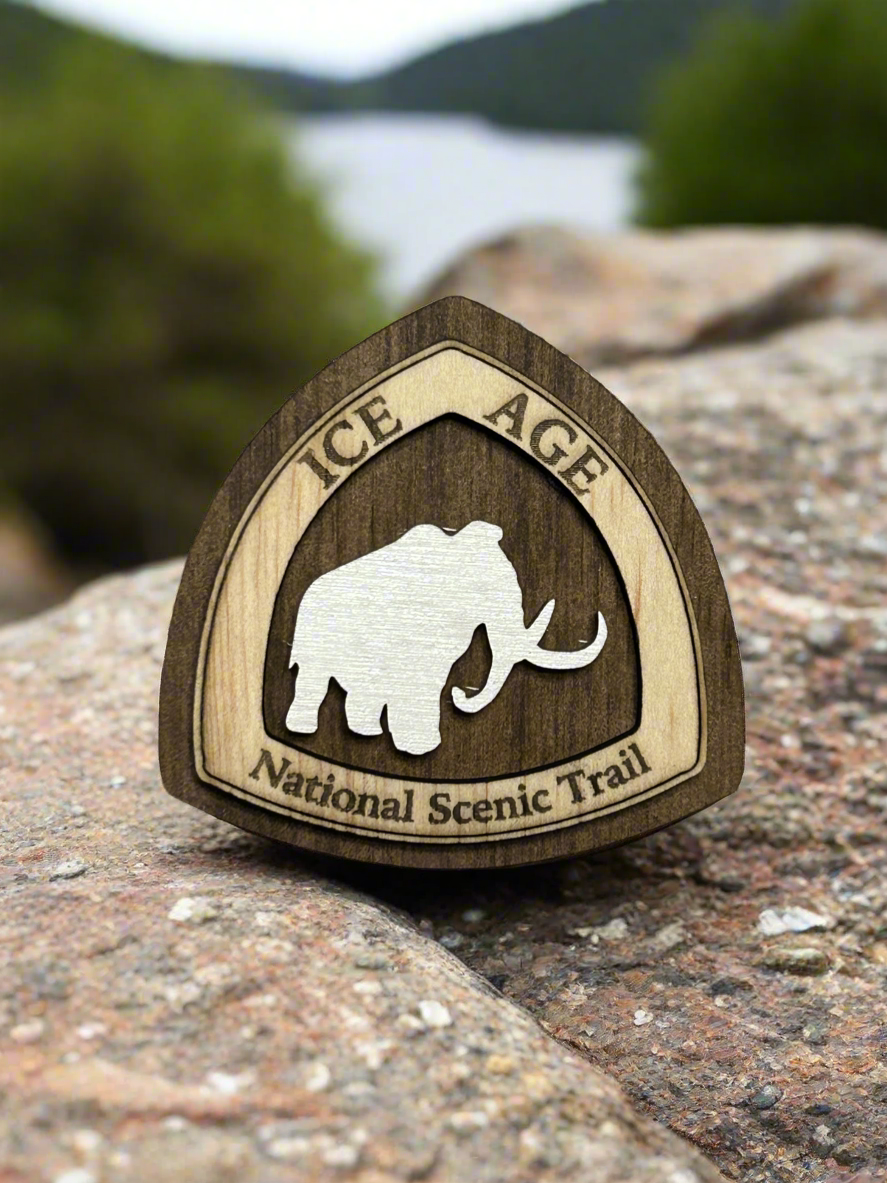 National Trail Icon with Text "Ice Age National Scenic Trail" and a White Mammoth Icon on a walnut colored background. 