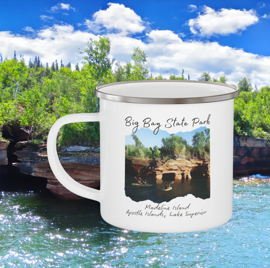 White enamel mug with picture depicting kayakers in front of sea caves and the text “Big Bay State Park - Madeline Island, Apostle Islands, Lake Superior.  Photo background: sea caves.