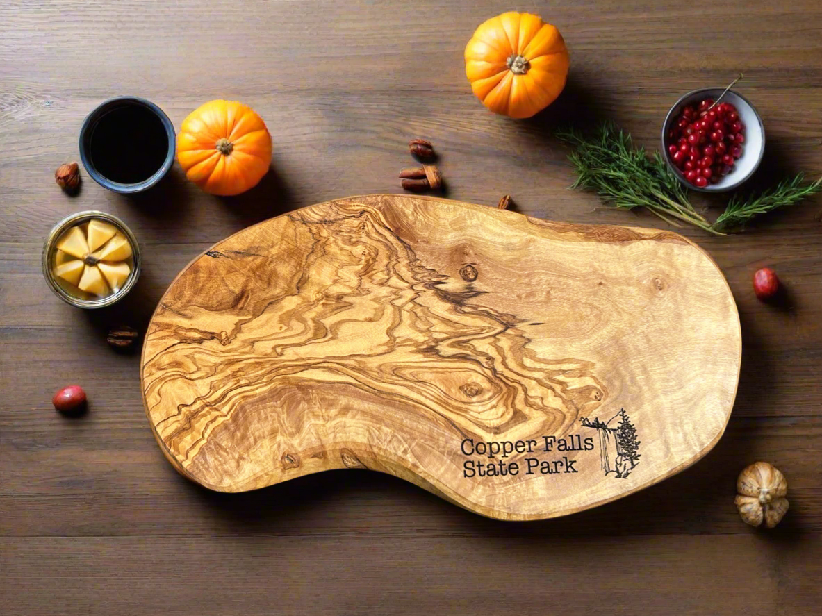 Rustic irregularly shaped olivewood serving board with the Text "Copper Falls State Park" and a waterfall icon. 