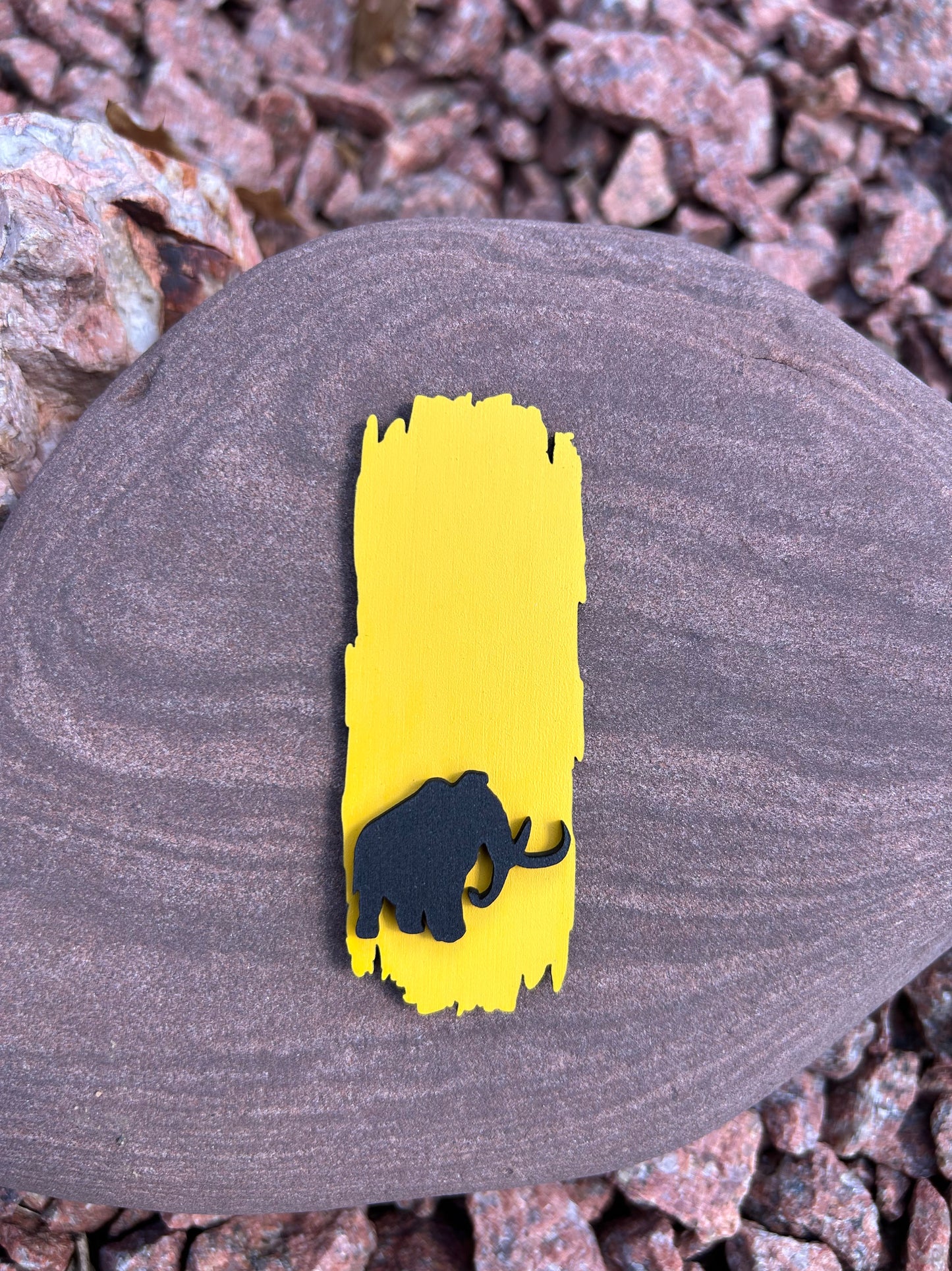 Yellow painted wood National Trail Blaze magnet with a black mammoth icon on the bottom half of the magnet. 