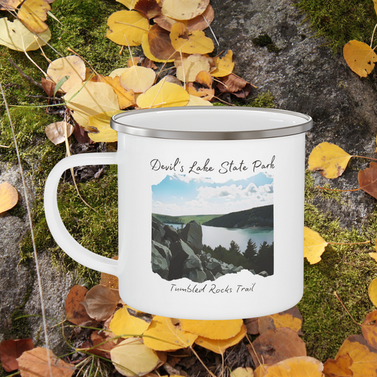 White enamel campfire mug with picture overlooking Devil’s Lake and the text Devil’s Lake State Park, Tumbled Rocks Trail.  Background: yellow leaves and moss.